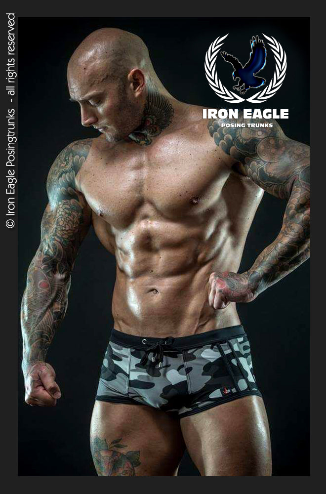 Muscular model wearing gray and black camouflage low-rise posing trunks with a wide black waistband. - Low Rise Trunks - camouflage - M